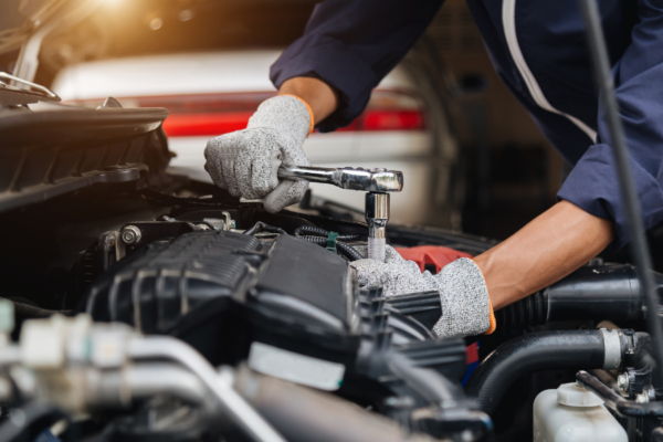 Automobilový technik při práci na vozidle v servisu.
