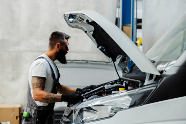 Automechanik provádějící kontrolu motoru u moderního vozu